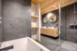 This modern bathroom features a sleek design with gray tile walls and flooring, complemented by a warm wooden ceiling.