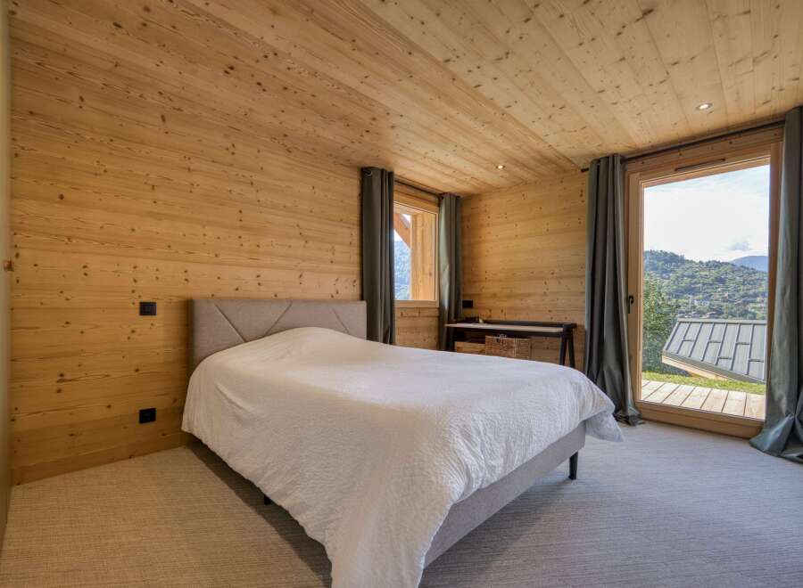 This cozy bedroom features stunning wooden paneling on the walls and ceiling, creating a warm and inviting atmosphere.
