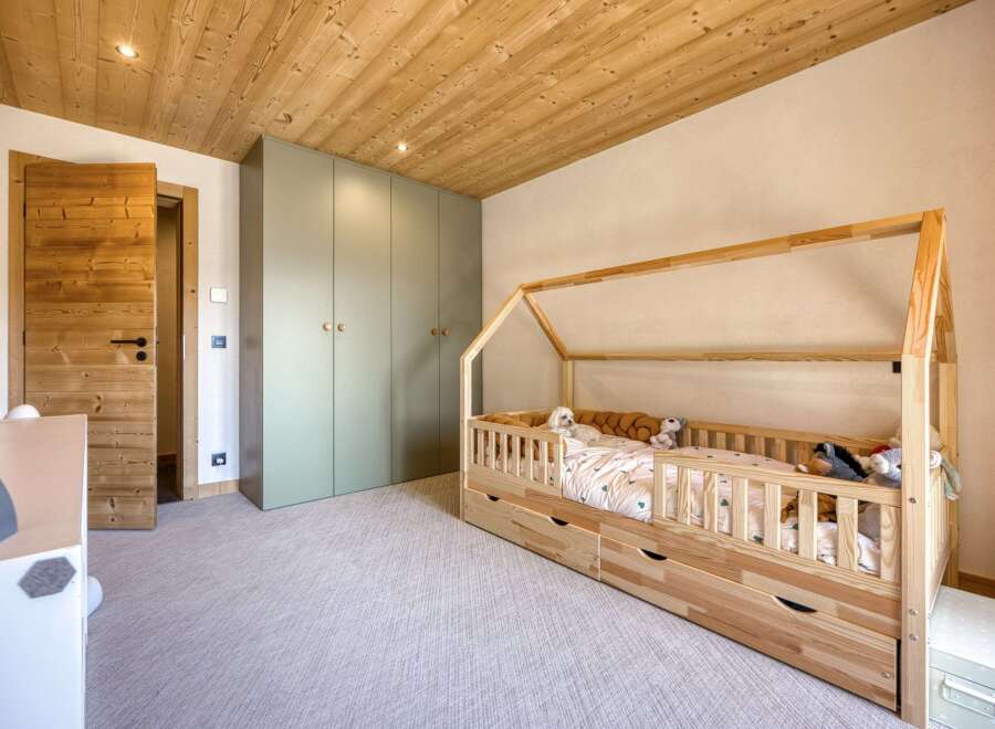 This charming bedroom features a cozy wooden bed frame and a spacious wardrobe, perfect for a child's sanctuary.