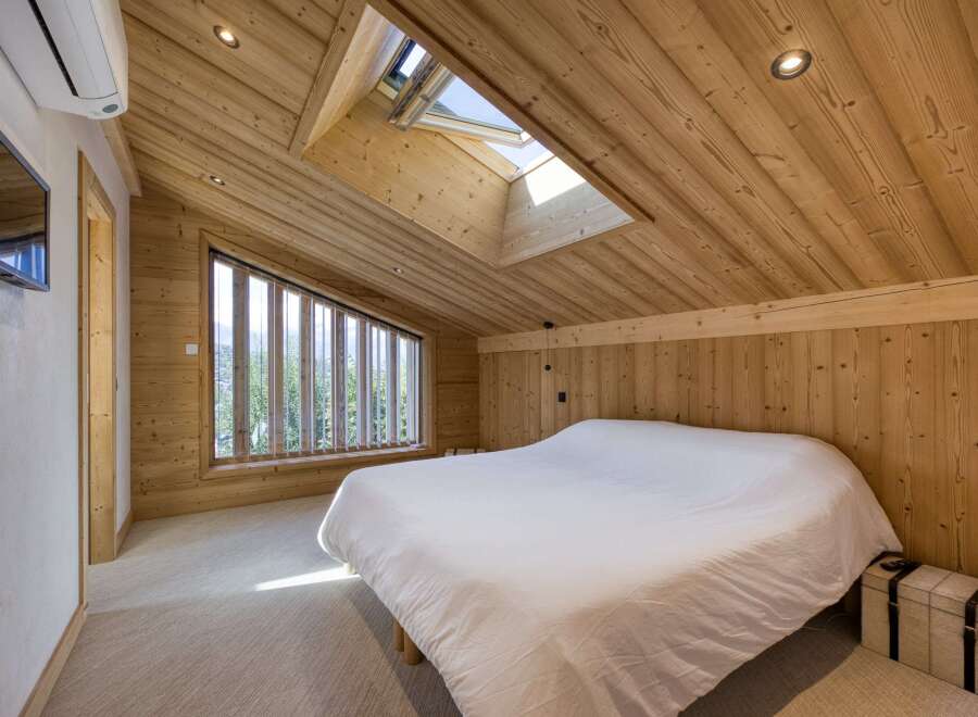 This stunning bedroom showcases a unique architectural design with its wooden sloped ceiling and walls, creating a warm and inviting atmosphere.