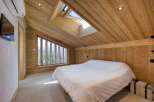 This stunning bedroom showcases a unique architectural design with its wooden sloped ceiling and walls, creating a warm and inviting atmosphere.