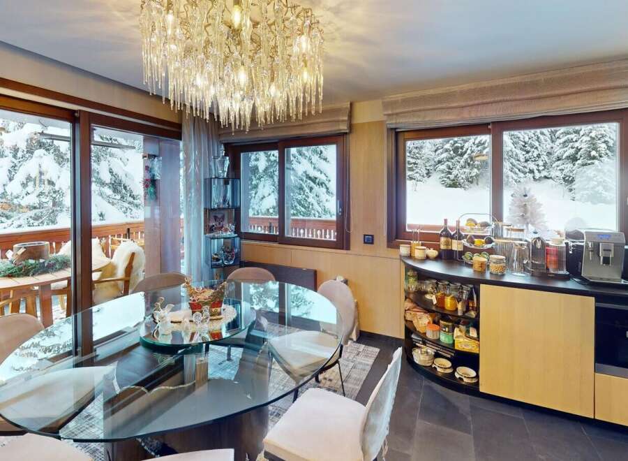 Experience the epitome of luxury living in this stunning property, featuring a sophisticated dining area with a breathtaking view of snow-covered landscapes.