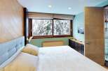 Experience the tranquility of this stunning bedroom, featuring a cozy bed and a breathtaking view of a snow-covered landscape through the large windows.