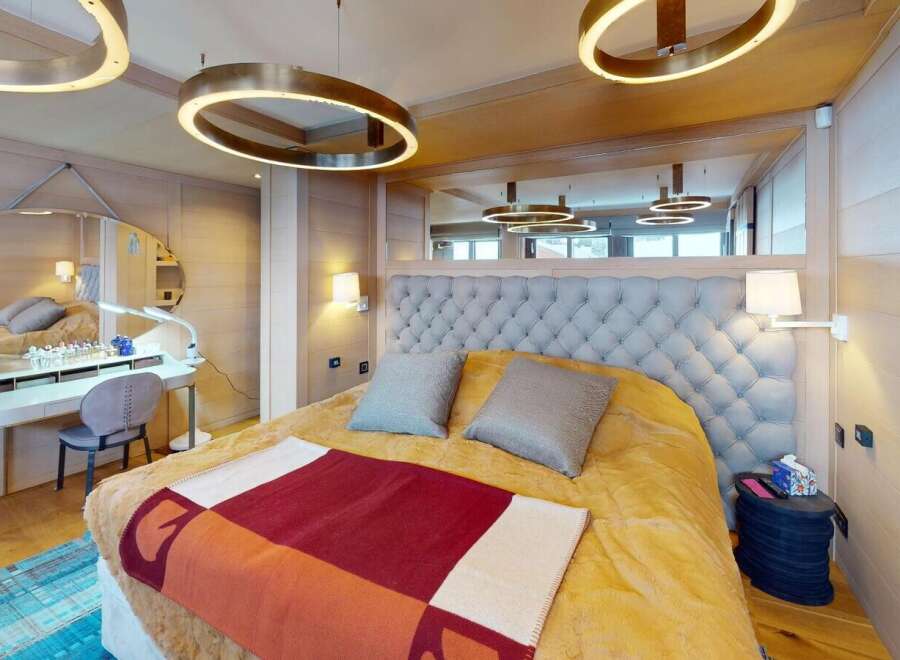Experience luxury in this stunning bedroom, featuring a plush tufted headboard and elegant lighting fixtures.