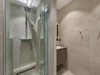 Step into a modern bathroom oasis! This stunning space features a sleek glass-enclosed shower with a rainfall showerhead, complemented by stylish tile work.
