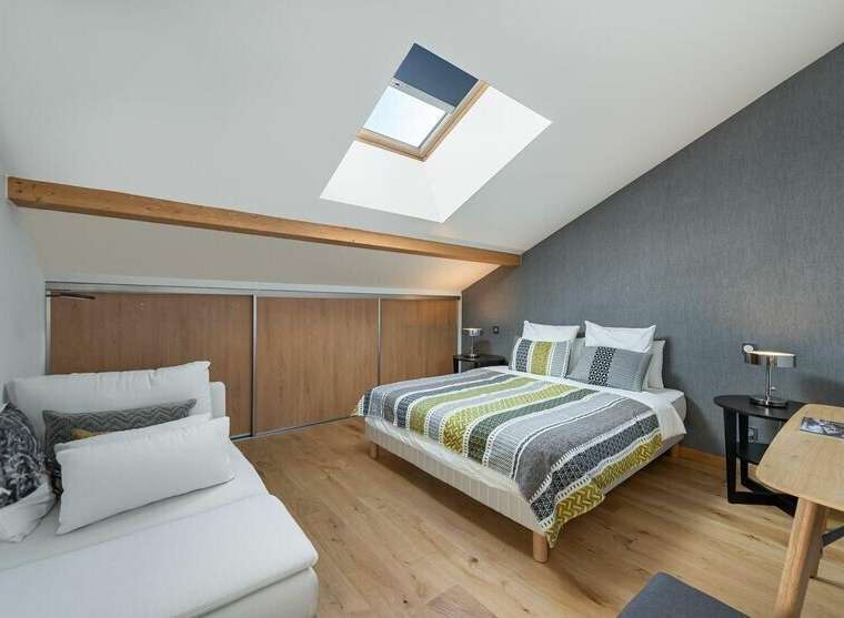This charming bedroom features a unique design with a skylight and wooden beams, creating a bright and airy atmosphere.