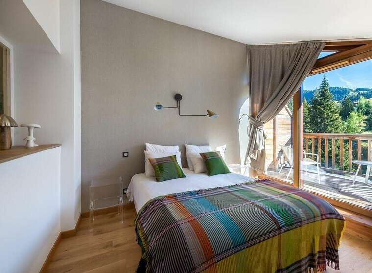Experience the tranquility of this stunning bedroom, featuring a cozy bed adorned with colorful blankets and pillows.