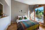 Experience the tranquility of this stunning bedroom, featuring a cozy bed adorned with colorful blankets and pillows.