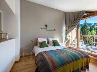 Experience the tranquility of this stunning bedroom, featuring a cozy bed adorned with colorful blankets and pillows.