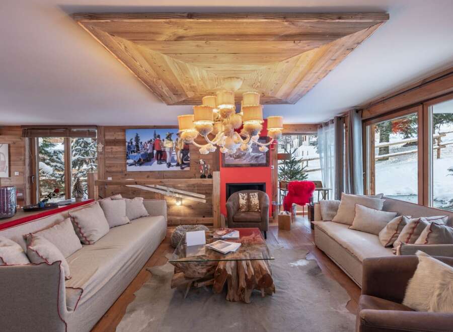 Experience luxury living in this stunning chalet, featuring a cozy living room with a fireplace and comfortable seating.