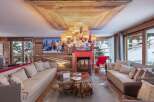 Experience luxury living in this stunning chalet, featuring a cozy living room with a fireplace and comfortable seating.