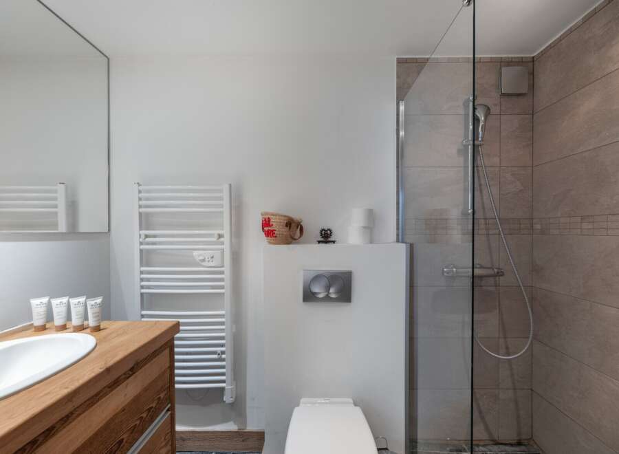 This modern bathroom features a sleek design with a wooden vanity and a white sink.