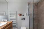 This modern bathroom features a sleek design with a wooden vanity and a white sink.
