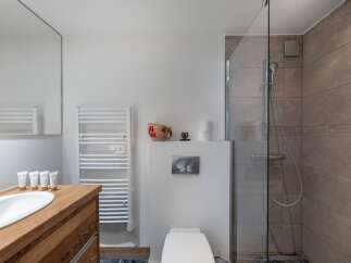 This modern bathroom features a sleek design with a wooden vanity and a white sink.
