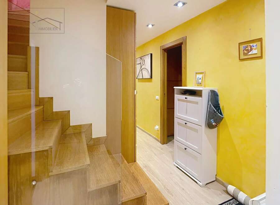 Step into this inviting entryway, showcasing a beautiful wooden staircase and a bright, yellow-painted hallway.