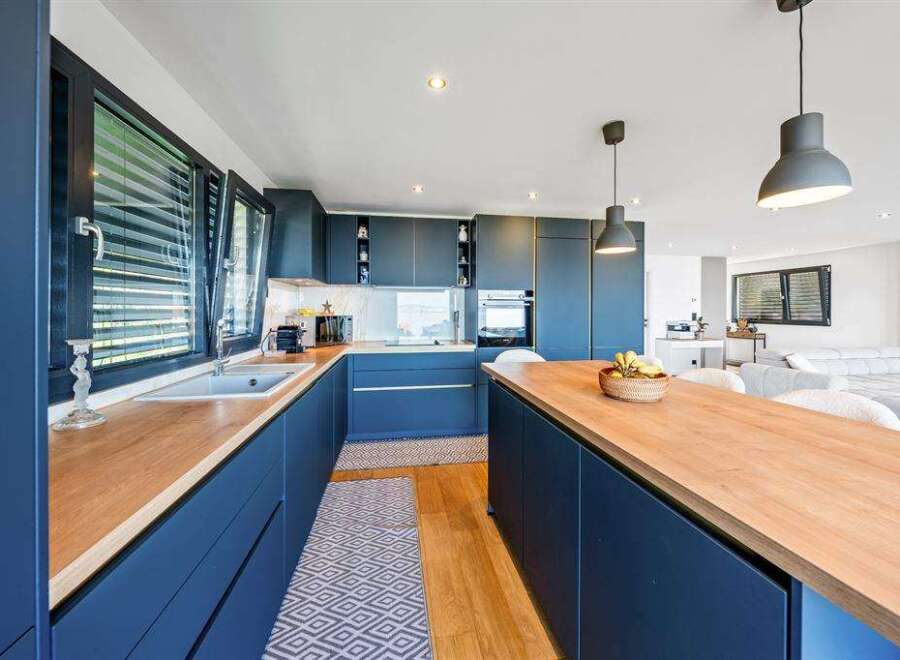Discover modern elegance in this stunning kitchen, featuring sleek navy cabinetry and warm wooden countertops.