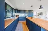 Discover modern elegance in this stunning kitchen, featuring sleek navy cabinetry and warm wooden countertops.