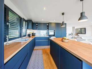 Discover modern elegance in this stunning kitchen, featuring sleek navy cabinetry and warm wooden countertops.