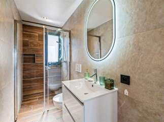 Step into a modern bathroom oasis, featuring a sleek white vanity and a stylish, illuminated mirror.