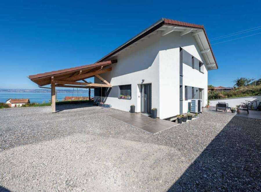 This stunning property boasts a modern design with a bright white exterior and a charming wooden carport.
