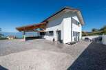 This stunning property boasts a modern design with a bright white exterior and a charming wooden carport.