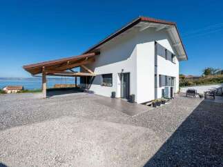 This stunning property boasts a modern design with a bright white exterior and a charming wooden carport.