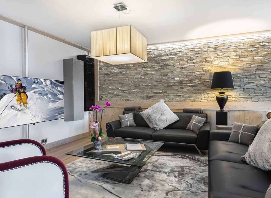 Experience luxury living in this stunning property, featuring a modern living room with a sleek black leather sofa and a stylish glass coffee table.