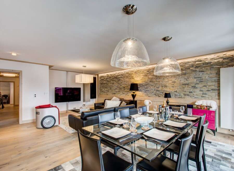 Experience luxury living in this stunning property, featuring a modern dining area with a glass table and stylish black chairs.