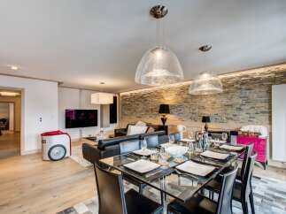 Experience luxury living in this stunning property, featuring a modern dining area with a glass table and stylish black chairs.