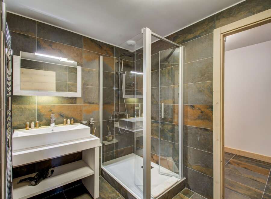 Step into luxury with this stunning bathroom featuring a modern glass shower enclosure and elegant tile work.