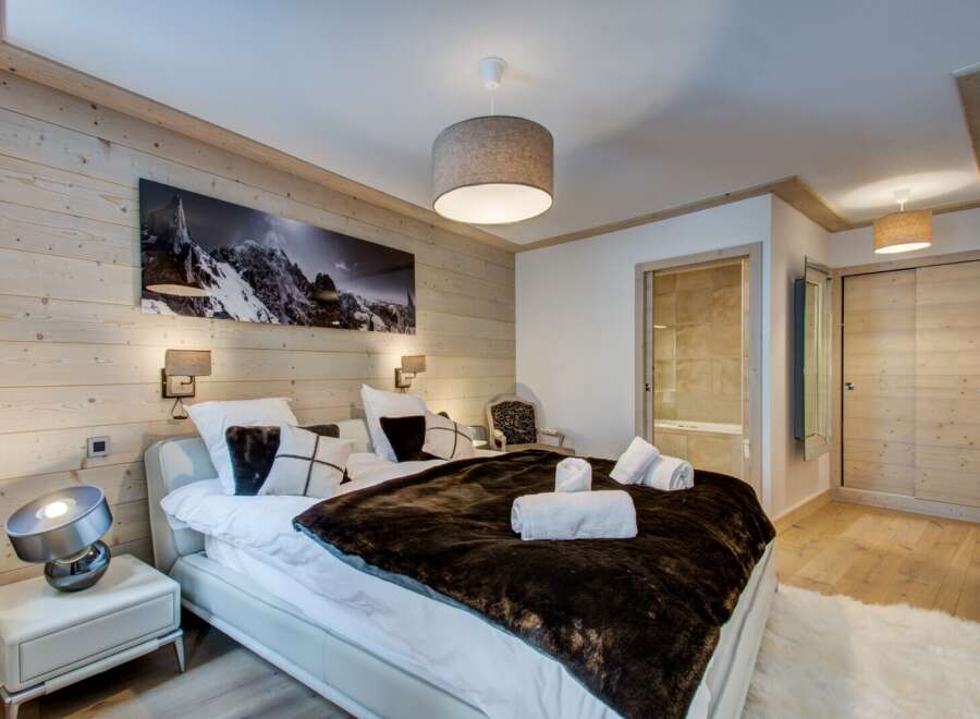 Experience luxury in this stunning bedroom featuring a cozy bed adorned with plush pillows and a faux fur throw.
