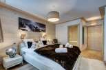 Experience luxury in this stunning bedroom featuring a cozy bed adorned with plush pillows and a faux fur throw.