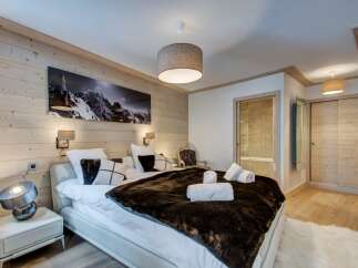 Experience luxury in this stunning bedroom featuring a cozy bed adorned with plush pillows and a faux fur throw.