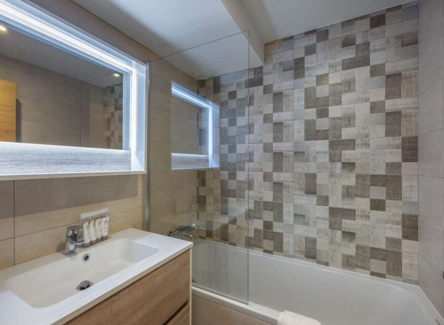This modern bathroom features a sleek design with a combination of light and dark tiles, creating a stylish and inviting atmosphere.