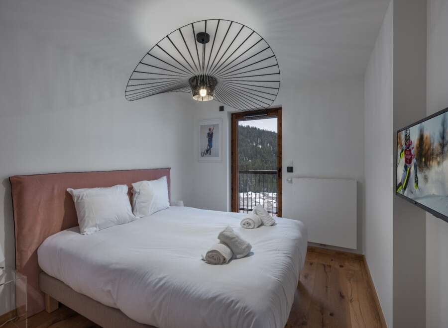 Experience luxury in this stunning bedroom featuring a plush bed and a unique, modern light fixture.