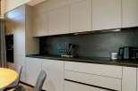 This modern kitchen boasts sleek, minimalist design with ample storage and a dark backsplash.