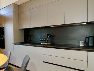 This modern kitchen boasts sleek, minimalist design with ample storage and a dark backsplash.