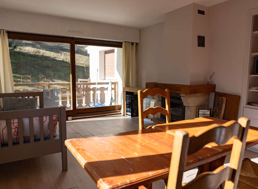 This charming property features a cozy living space with a rustic wooden dining table and chairs, perfect for family gatherings.