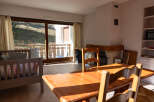 This charming property features a cozy living space with a rustic wooden dining table and chairs, perfect for family gatherings.