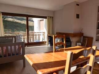 This charming property features a cozy living space with a rustic wooden dining table and chairs, perfect for family gatherings.