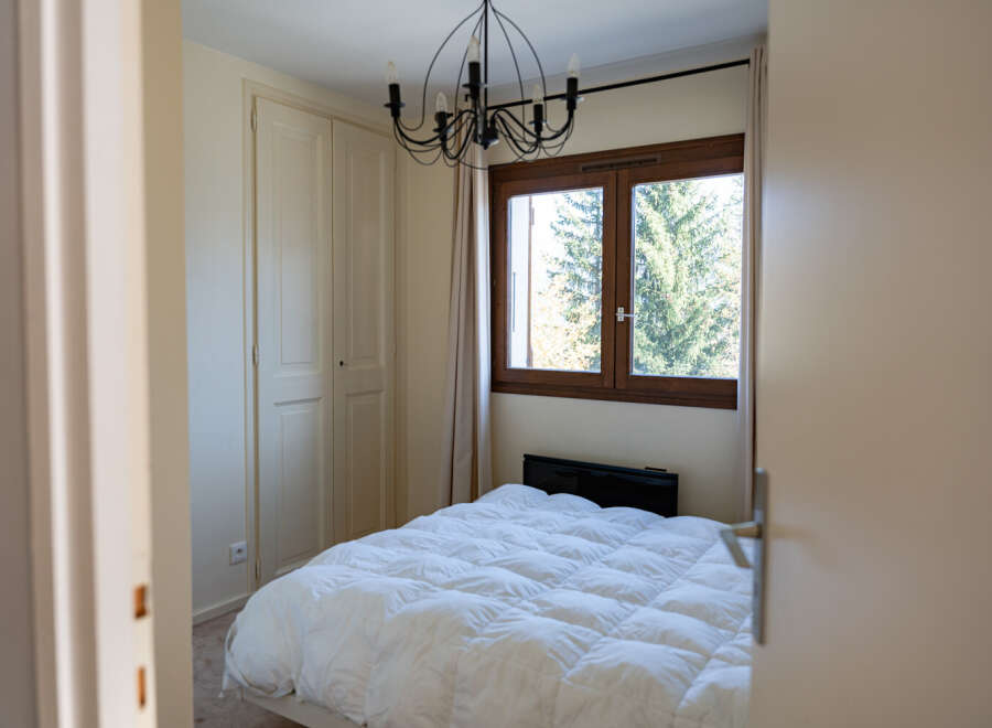 This cozy bedroom features a comfortable bed with a fluffy white comforter, perfect for a relaxing retreat.