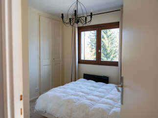 This cozy bedroom features a comfortable bed with a fluffy white comforter, perfect for a relaxing retreat.