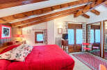 This charming bedroom features a cozy ambiance with its wooden beams and red accents.