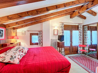 This charming bedroom features a cozy ambiance with its wooden beams and red accents.