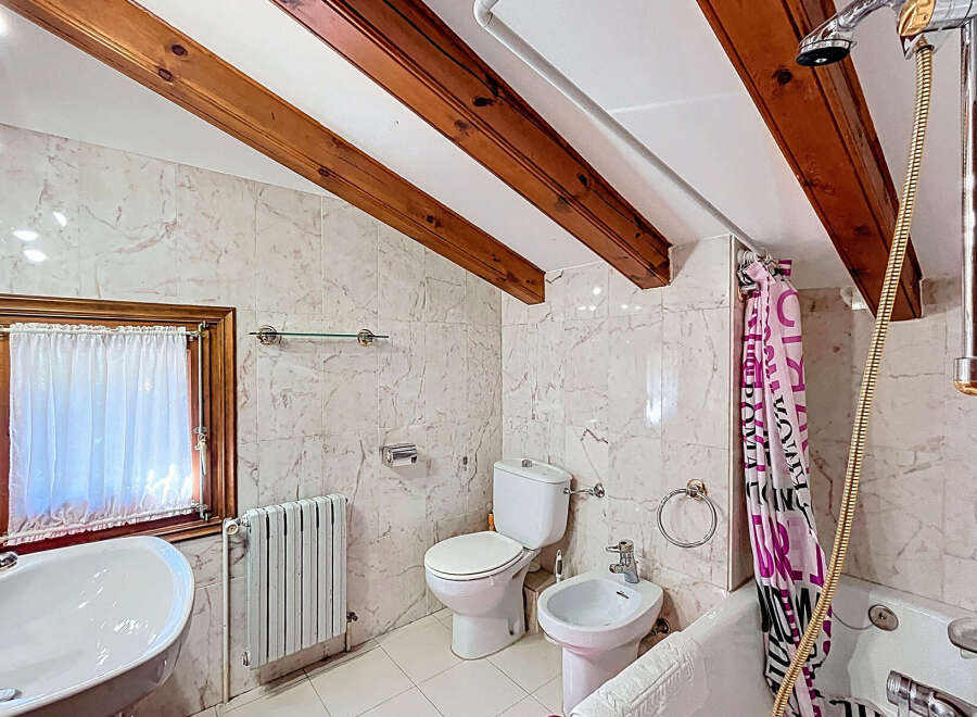 This charming bathroom features a unique design with exposed wooden beams on the ceiling, adding character and warmth.