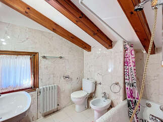 This charming bathroom features a unique design with exposed wooden beams on the ceiling, adding character and warmth.