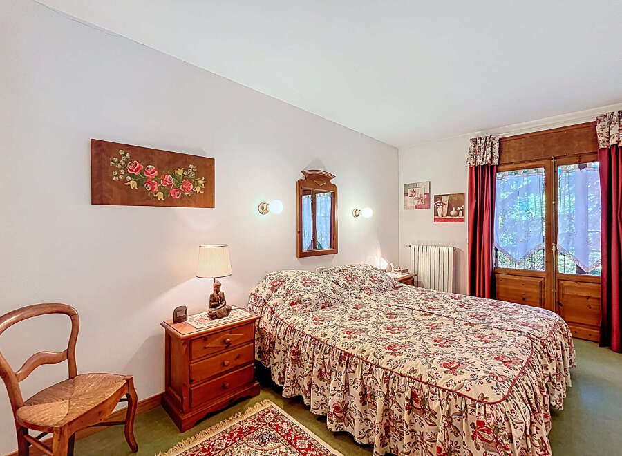 This charming bedroom features a cozy double bed with a floral patterned bedspread, creating a warm and inviting atmosphere.
