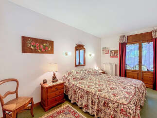 This charming bedroom features a cozy double bed with a floral patterned bedspread, creating a warm and inviting atmosphere.