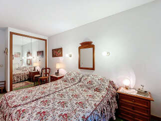 Discover the charm of this cozy bedroom, featuring a comfortable bed with a floral patterned bedspread.