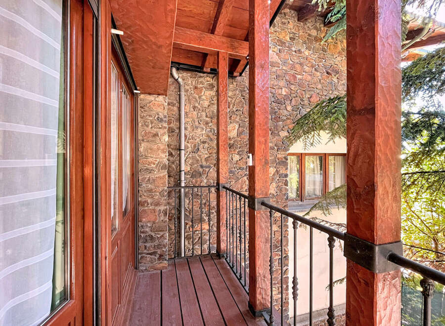 This stunning property boasts a charming balcony with intricate wooden detailing and a rustic stone facade.